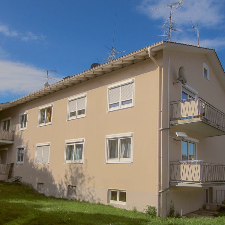 Ein Wohnhaus mit Balkons neben einer Rasenfläche