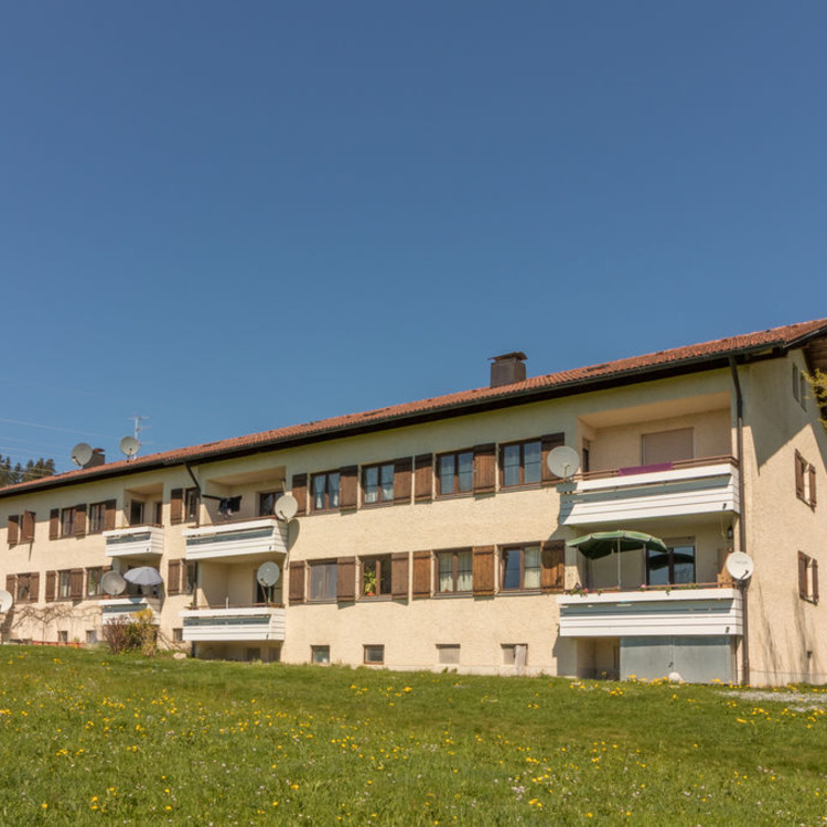 Ein Mehrfamilienhaus neben einer Rasenfläche