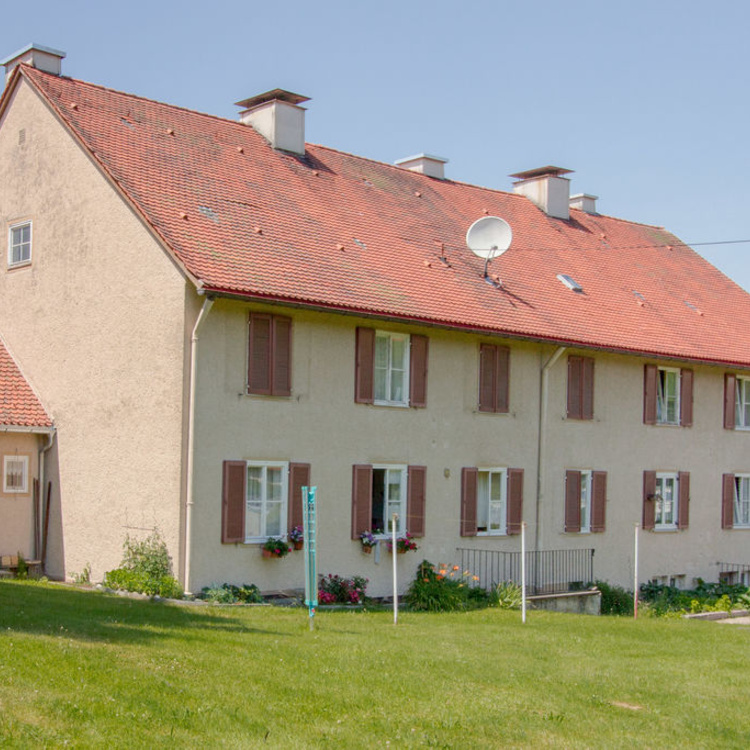 Ein Mehrfamilienhaus neben einer Wiese