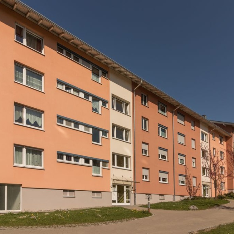 Ein Mehrfamilienhaus mit hellroter Fassade