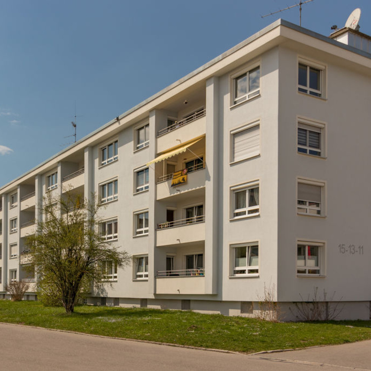 Ein Mehrfamilienhaus neben einer Rasenfläche