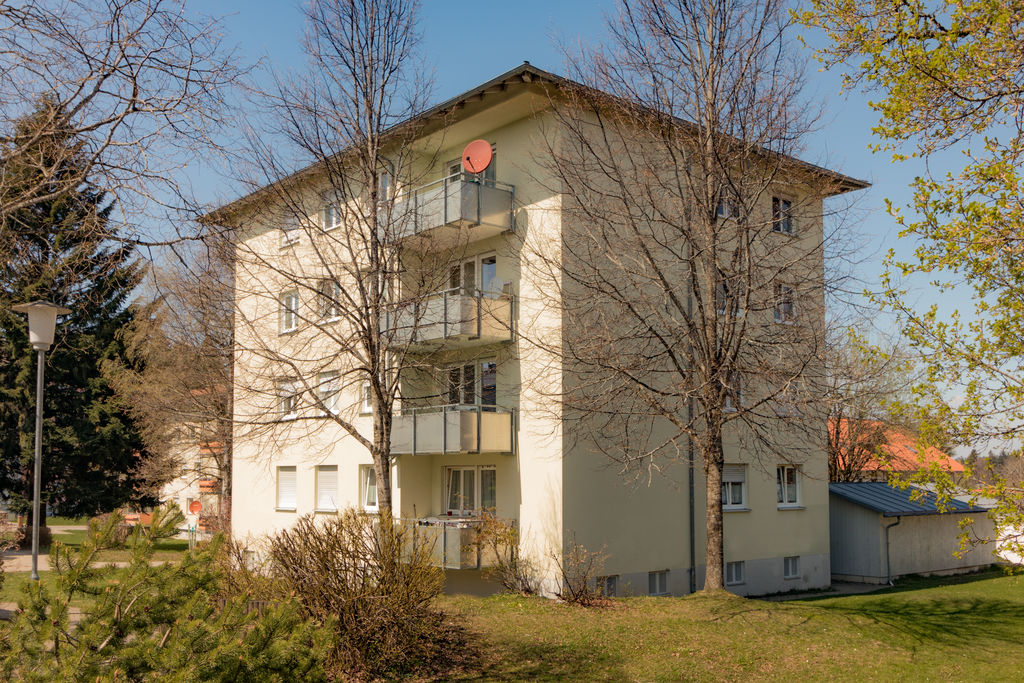 Ein Mehrfamilienhaus hinter Bäumen