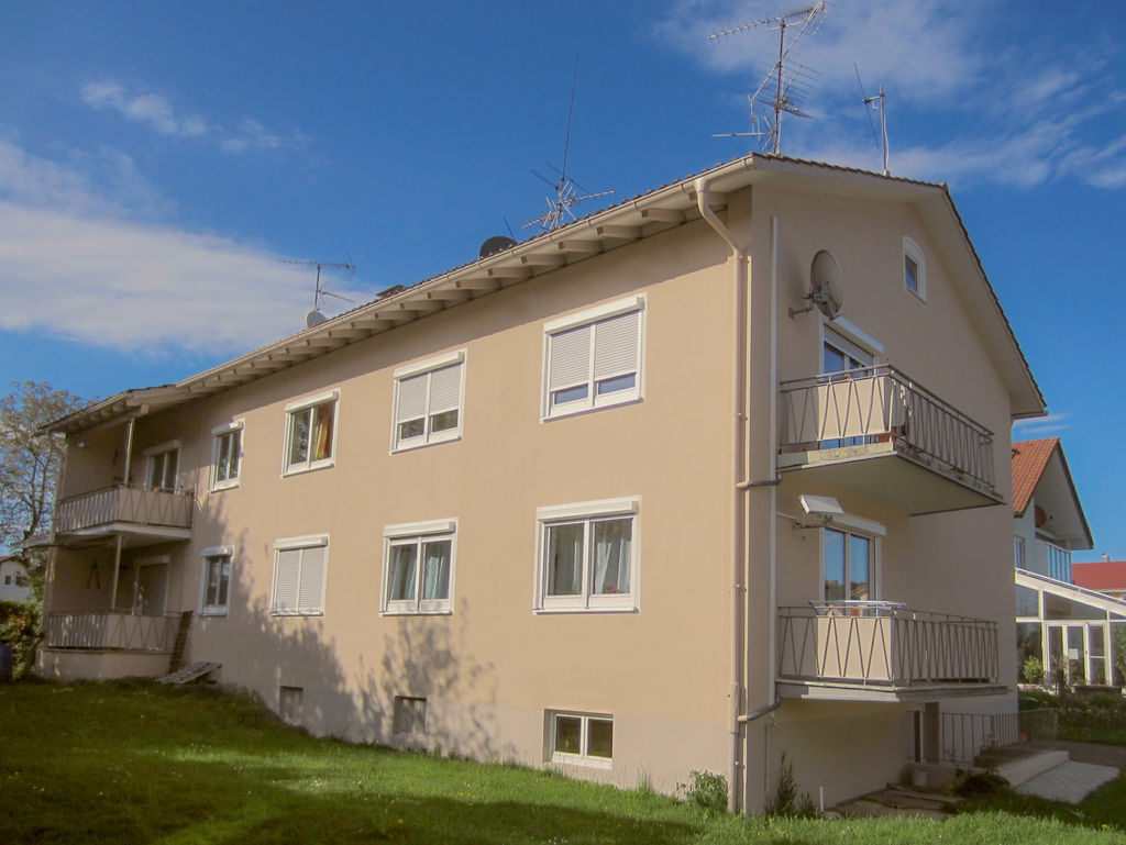 Ein Wohnhaus mit Balkons neben einer Rasenfläche